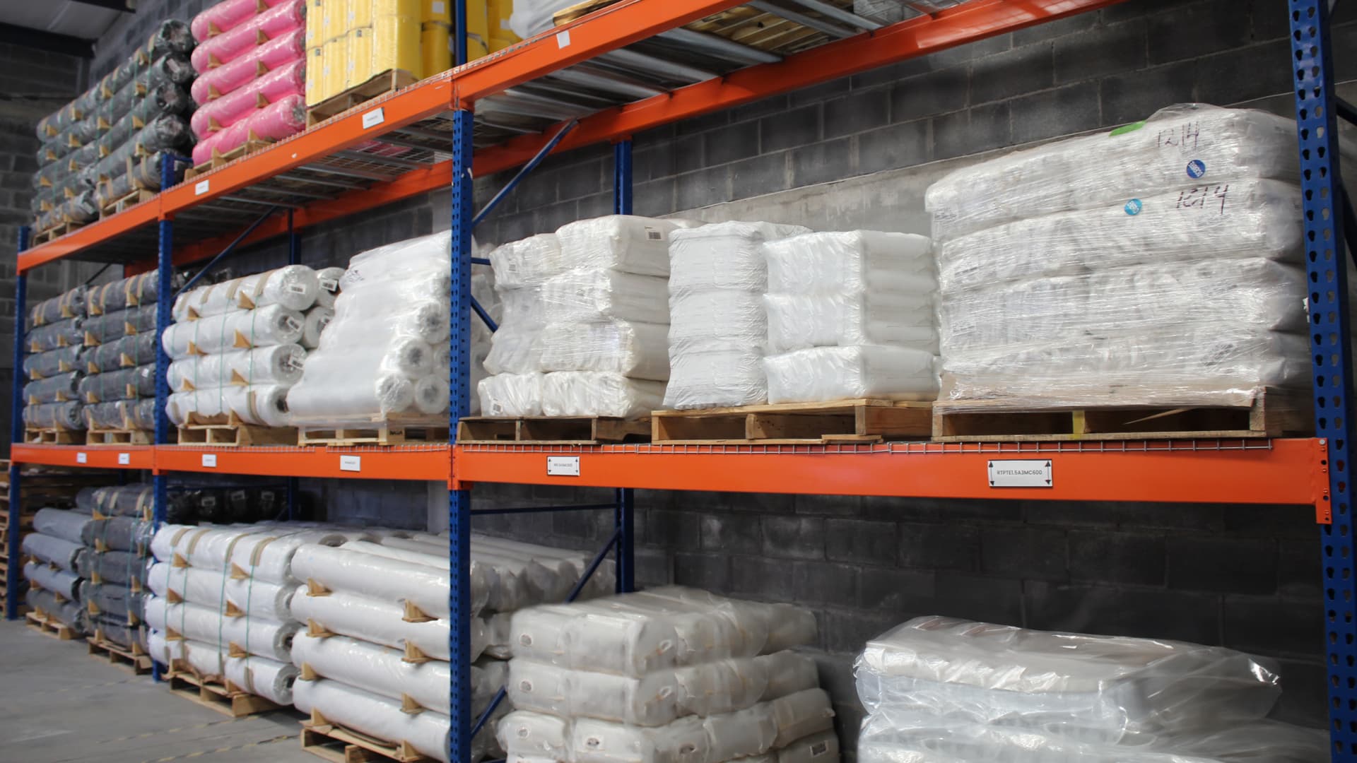 Bodega industrial con racks de rollos de polietileno embalados